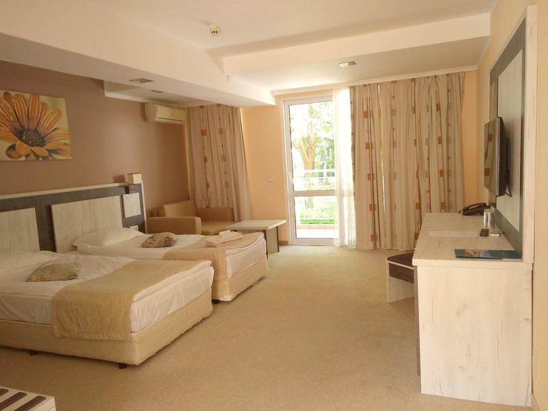 Lichte hotelkamer met twee eenpersoonsbedden, balkon en moderne tv.