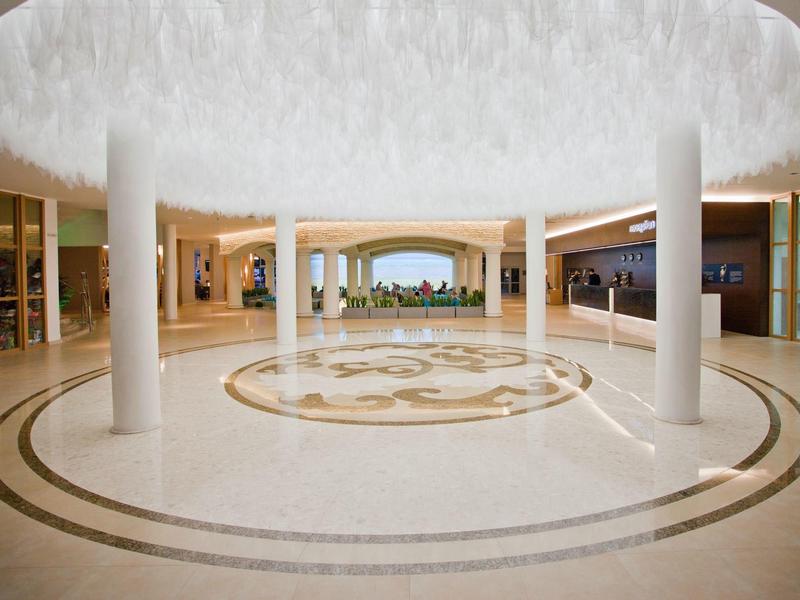 Ruime hotellobby met ronde lichte plafond en zuilen, met uitzicht op tuin op de achtergrond