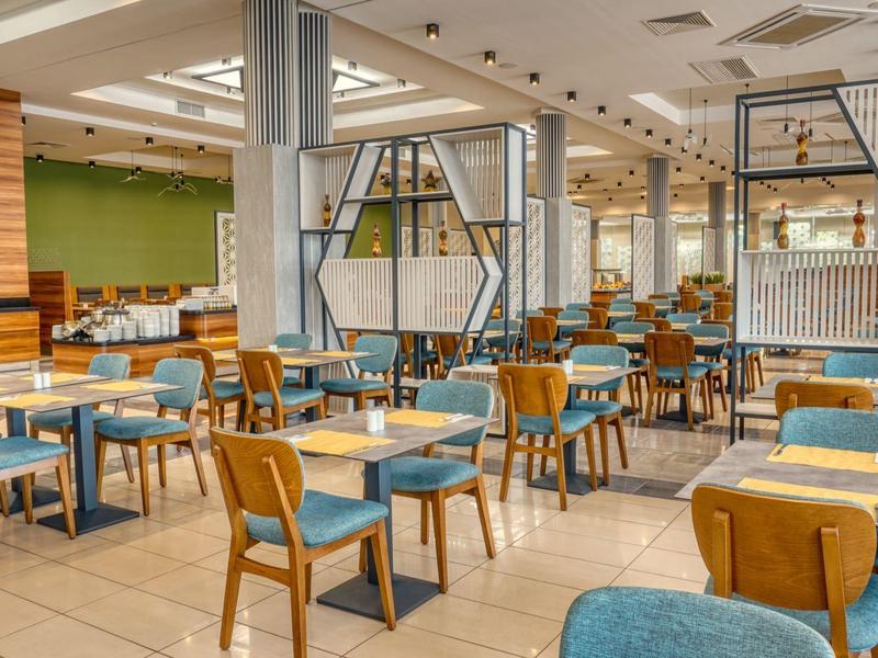 Licht, modern restaurant met blauwe beklede stoelen en houten meubels in een hotel.