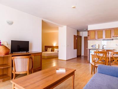 Bright hotel room with seating area, dining table, and open kitchen.