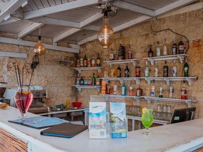 Bar with white marble countertops, wine bottle shelves, and rustic stone walls.
