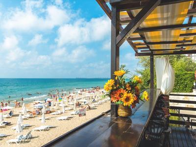 Hotelgebouw aan het strand met parasols en mensen bij het water