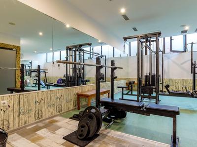 Moderne fitnessruimte met krachtapparatuur en spiegelwand in lichte omgeving.