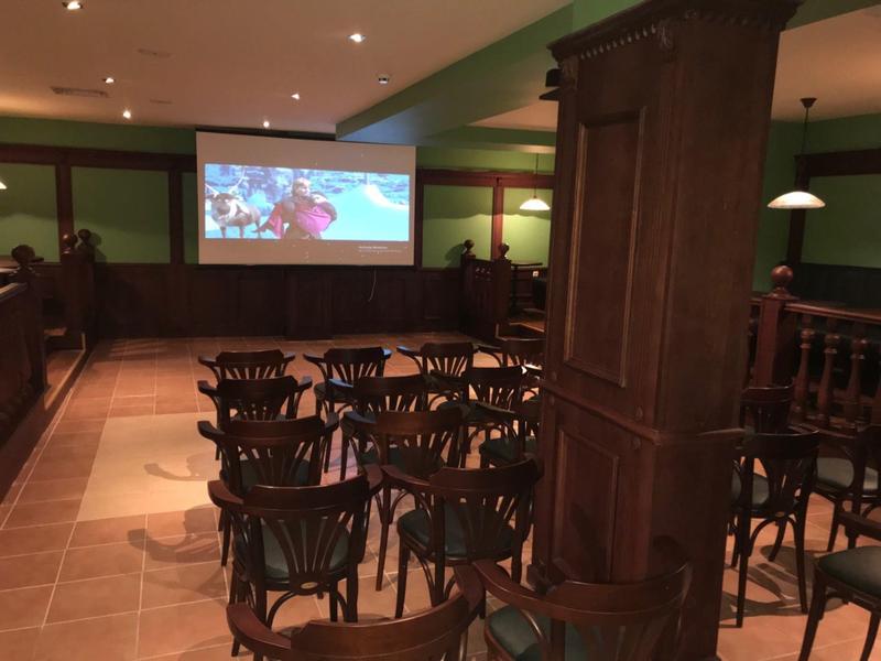 Conference room with rows of chairs and a projection screen on the wall.