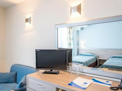 Modern hotel room with TV, desk, blue sofa, and mirror.