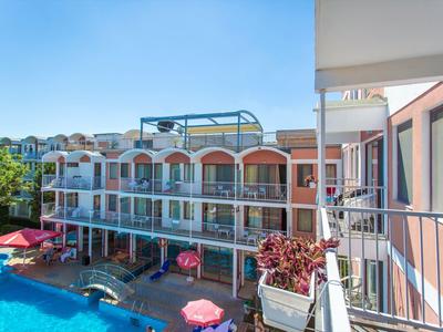 View of a multi-story hotel with balconies and a pool in the foreground under a blue sky