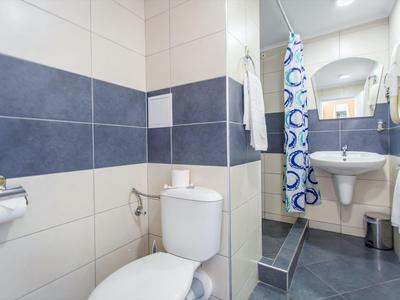 Modern bathroom with toilet, sink, and shower with blue and white shower curtain.