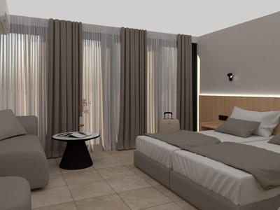 Moderně zařízený hotelový pokoj s manželskou postelí, sedací částí a velkými okny se závěsy.