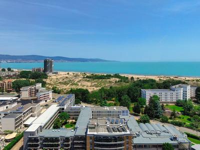 Moderner Hotelkomplex mit Flachdächern, umgeben von Grünflächen und Blick auf das blaue Meer.