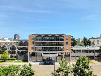 Mehrstöckiges Hotelgebäude mit Glasfront und Parkplätzen bei klarem Himmel.