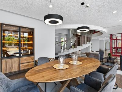 Moderner Hotel-Loungebereich mit Holztisch, schwarzen Sitzsäcken und weißer Treppe im Hintergrund.