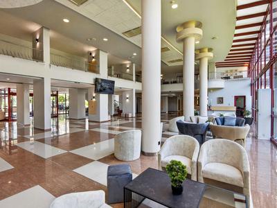 Großer, heller Hotellobby-Bereich mit Sitzgruppen und großen Fenstern.