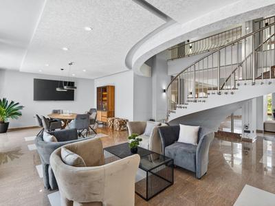 Modern eingerichtetes Hotelzimmer mit geschwungener Treppe und gemütlichen Sitzbereichen.
