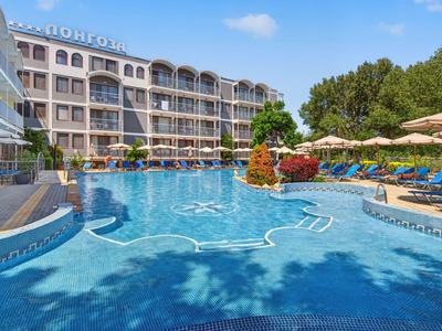 Moderner Hotelkomplex mit großem, blauen Außenpool und Liegestühlen unter Sonnenschirmen.