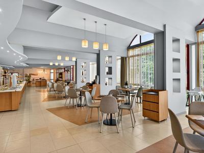 Geräumiger Hotel-Loungebereich mit modernen Möbeln, großen Fenstern und hellem Ambiente.
