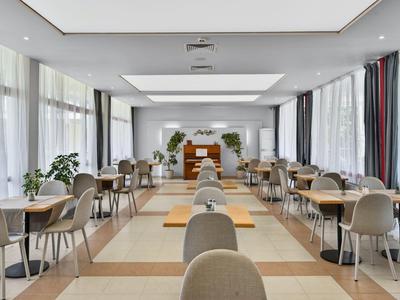 Helles, modernes Speisezimmer mit gedeckten Tischen und großen Fenstern.
