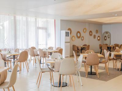 Jasna, nowoczesna restauracja z krzesłami i stołami w neutralnych kolorach.