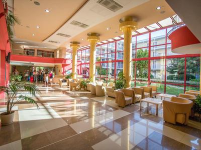Bright hotel lobby with large windows, yellow columns, and comfortable seating.