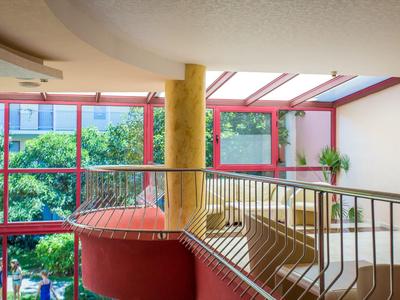 Open indoor space with large windows, plants, and cozy seating in the background.