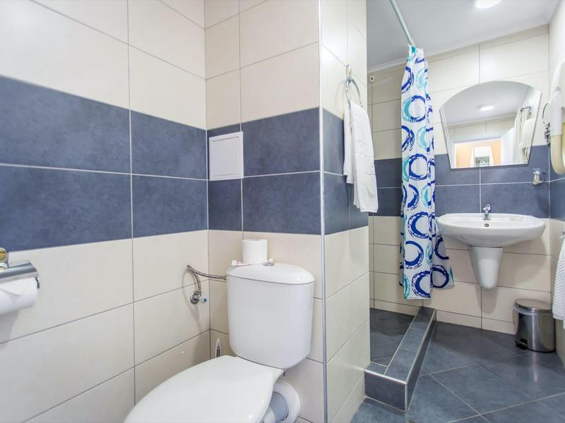 Modern bathroom with toilet, sink, and shower with blue and white shower curtain.