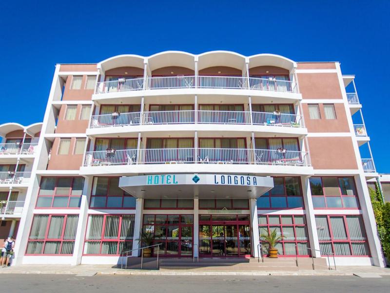 Modern multi-story hotel building with balconies and clear sky in the background.