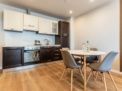 Moderner Küchenbereich mit holzfarbenen Schränken und kleinem Esstisch mit vier grauen Stühlen.