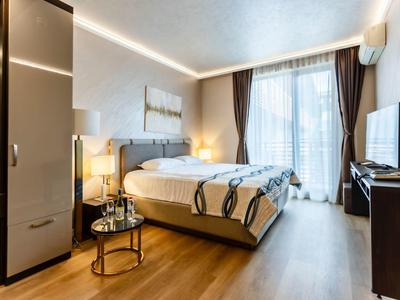 Modernes Hotelzimmer mit Doppelbett, TV, Schrank und Balkon mit Vorhängen