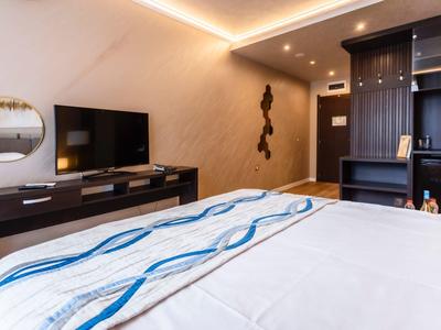 Modern eingerichtetes Hotelzimmer mit Bett, TV und Schrankwand.