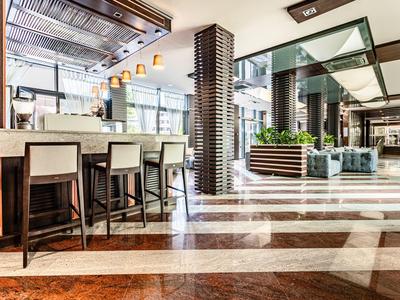 Heller Hotel-Lobbybereich mit Barhockern, Sitzbereich und modernen Designelementen.