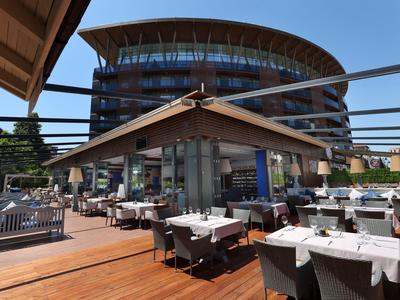 Nowoczesny zewnętrzny obszar hotelu z nakrytymi stołami i okrągłymi szklanymi elewacjami w tle.