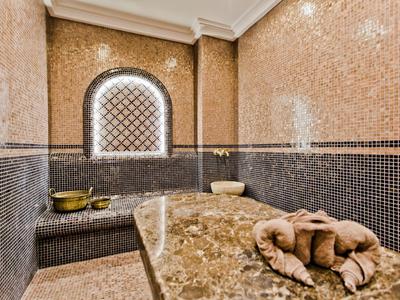 Innenraum eines türkischen Hammams mit Mosaikfliesen, einem beheizten Steintisch und Handtüchern.