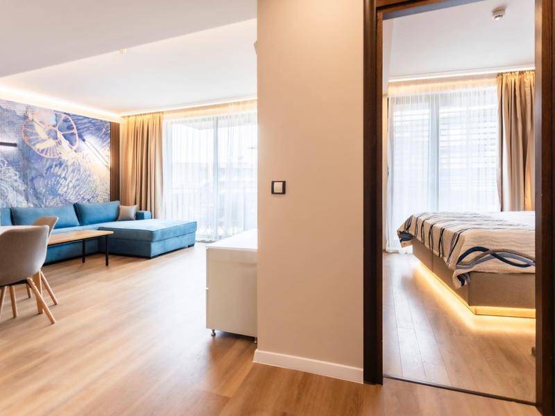 Modern eingerichtetes Hotelzimmer mit Wohnzimmer und Schlafzimmer mit Holzboden und großen Fenstern.