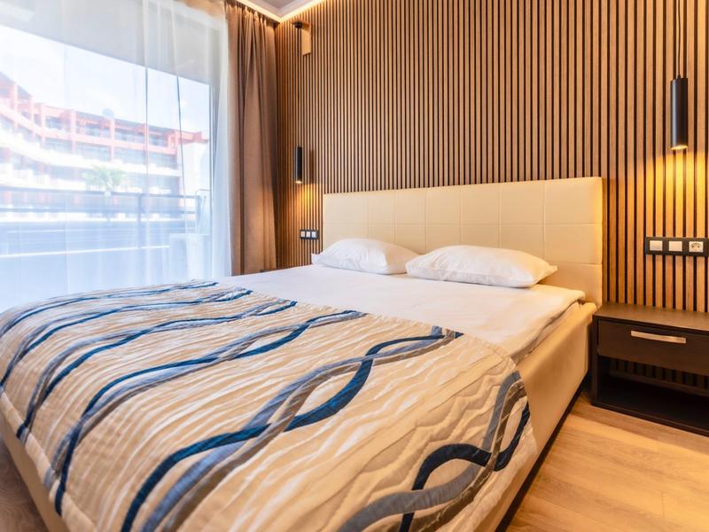 Modernes Schlafzimmer mit Holzwand, großem Bett, gemusterter Decke und großen Fenstern mit Vorhängen.