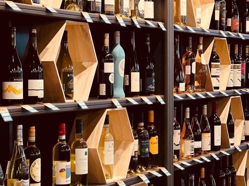 Weinregal mit vielen Flaschen und sechseckigen Holzboxen, angeordnet in mehreren Reihen.