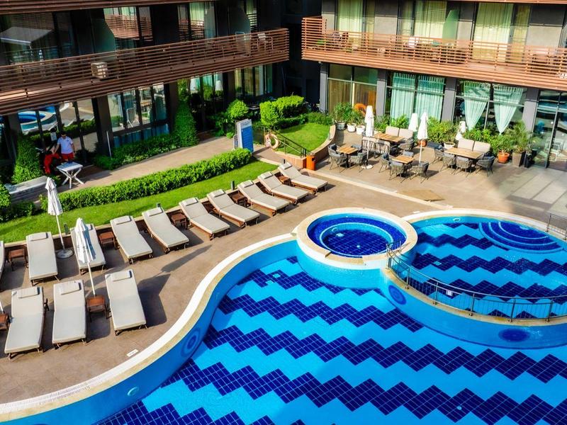 Moderner Hotelpool mit Sonnenschirmen und Liegestühlen in einer Innenhofanlage