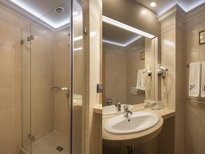 Moderne badkamer met glazen douche, verlichte spiegel, wastafel en netjes opgehangen handdoeken.