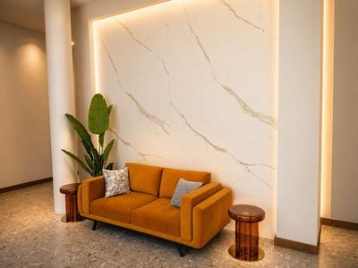 Modern eingerichteter Hotel-Loungebereich mit orangefarbenem Sofa, grüner Pflanze und stimmungsvoller Beleuchtung.