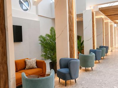 Moderne Hotellobby mit blauen Sesseln, braunem Sofa und viel natürlichem Licht.