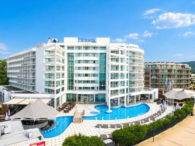 Nowoczesny hotel z białą elewacją i basenem pod niebieskim niebem.