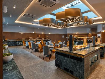 Nowoczesna część restauracyjna hotelu z stylowymi miejscami do siedzenia i stoiskami bufetowymi.
