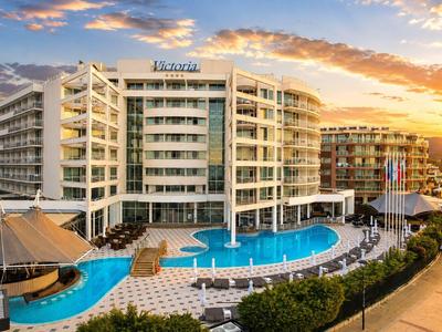 Nowoczesny budynek hotelowy z dużym basenem i miejscami do siedzenia o zachodzie słońca.