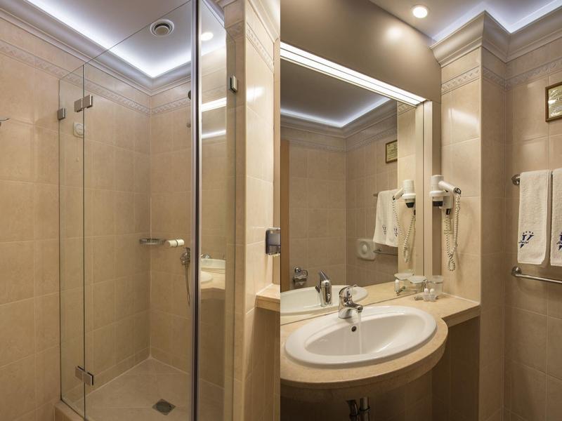 Moderne badkamer met glazen douche, verlichte spiegel, wastafel en netjes opgehangen handdoeken.