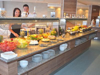Buffet with various foods and two people in the background in a restaurant.