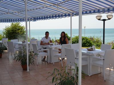 Taras restauracyjny z niebiesko-białymi markizami z widokiem na morze.