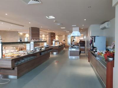 Modern, well-lit hotel dining area with various buffet stations and clean design.