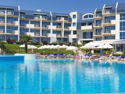 Duży wielopiętrowy hotel z przestronnym basenem na zewnątrz na pierwszym planie