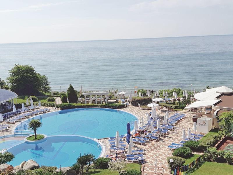 Hotel with large outdoor pool, sun loungers, and sea view.