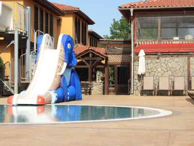 Kinder-Wasserrutsche neben einem Pool in einer Hotelanlage mit mediterranen Gebäuden im Hintergrund