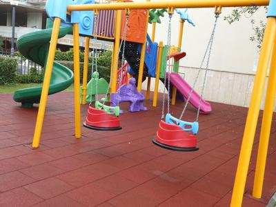 Colorful children's playground with swings, slide, and climbing frame on soft flooring