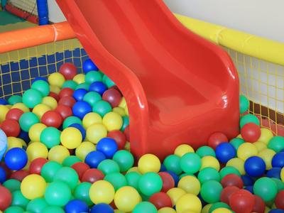 Red children's slide ends in a ball pit filled with colorful plastic balls.